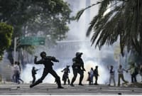 Cтолкновения между полицией и протестующими в Венесуэле. Полицейский бросает газовый баллончик в протестующих